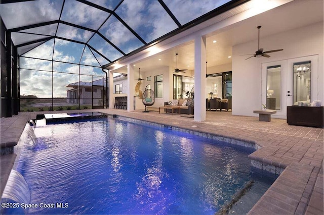 pool at dusk featuring a patio area, an outdoor hangout area, ceiling fan, and glass enclosure