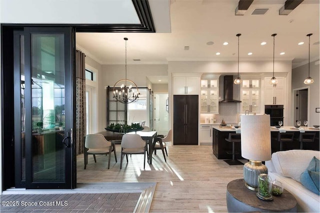 dining area with crown molding, light wood-type flooring, and a chandelier