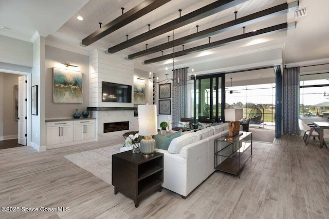 living room with light hardwood / wood-style flooring, ornamental molding, a notable chandelier, beamed ceiling, and a premium fireplace