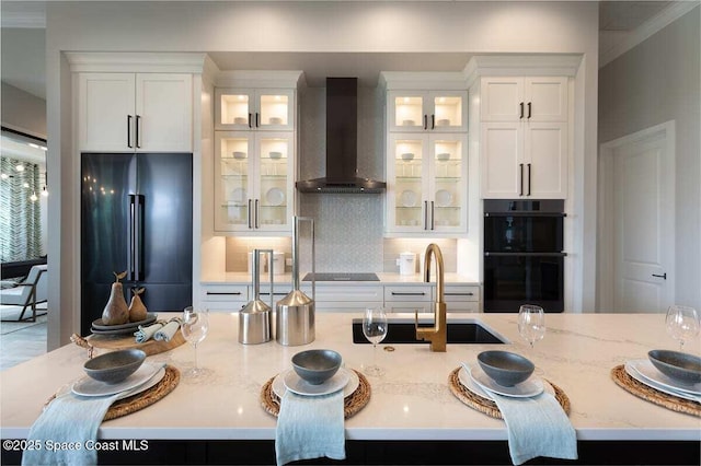 kitchen featuring white cabinets, wall chimney exhaust hood, light stone countertops, and black appliances