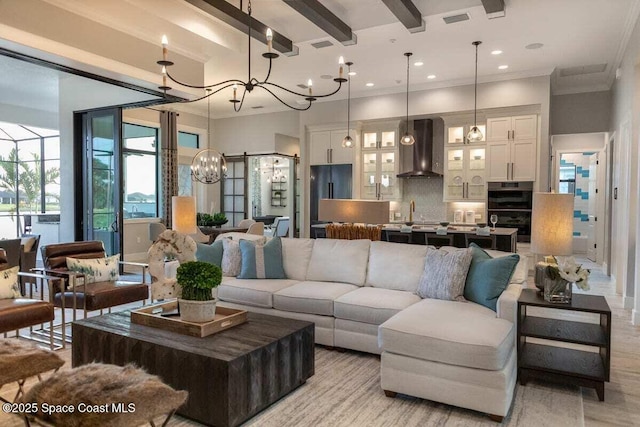 living room with crown molding, light wood-type flooring, sink, and a chandelier