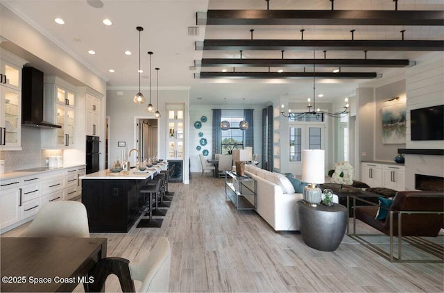 living room with sink, light wood-type flooring, ornamental molding, beamed ceiling, and a high end fireplace