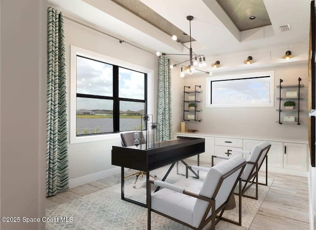 office area with a water view and light hardwood / wood-style flooring