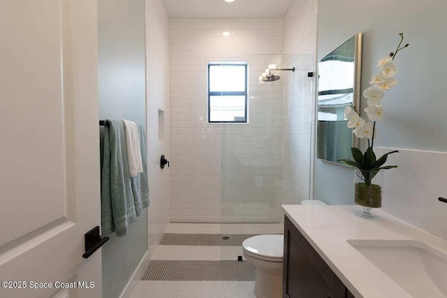 bathroom featuring vanity, tiled shower, tile patterned floors, and toilet