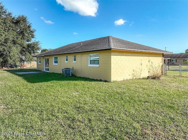 rear view of house featuring central AC and a lawn