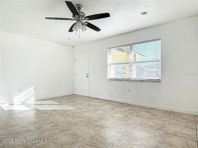 empty room featuring light tile patterned flooring, a textured ceiling, and ceiling fan