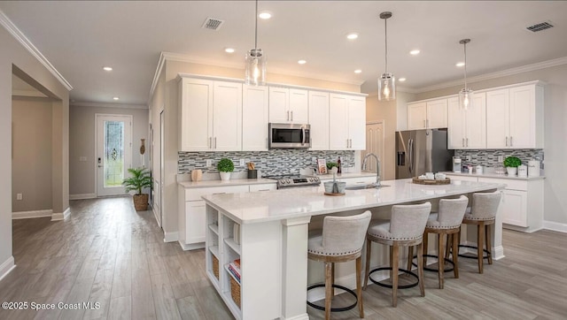 kitchen with stainless steel appliances, a kitchen island with sink, and white cabinets