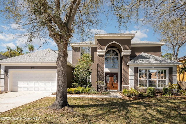 view of front of home with a garage, concrete driveway, a front yard, and stucco siding