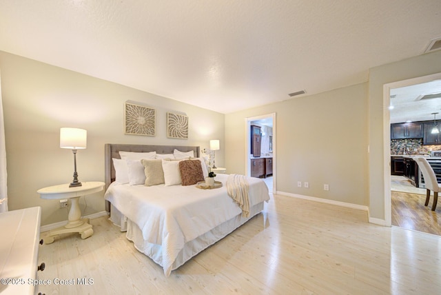 bedroom with connected bathroom and light wood-type flooring