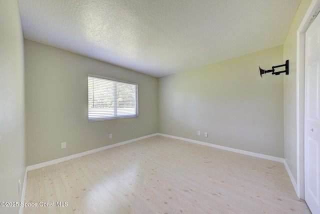 spare room with a textured ceiling and light wood-type flooring