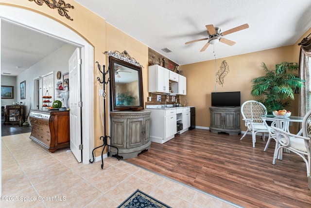 kitchen with light tile patterned floors, a textured ceiling, white cabinets, and ceiling fan