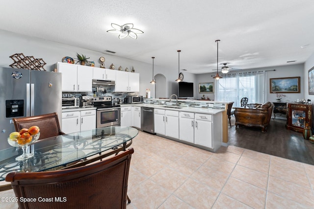 kitchen featuring sink, white cabinetry, hanging light fixtures, kitchen peninsula, and stainless steel appliances