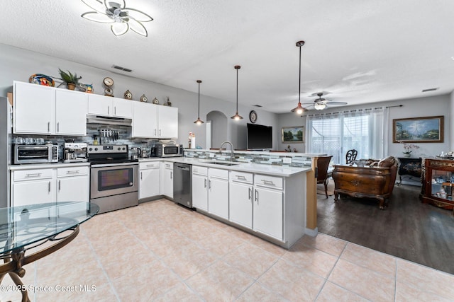 kitchen with sink, white cabinetry, hanging light fixtures, kitchen peninsula, and stainless steel appliances