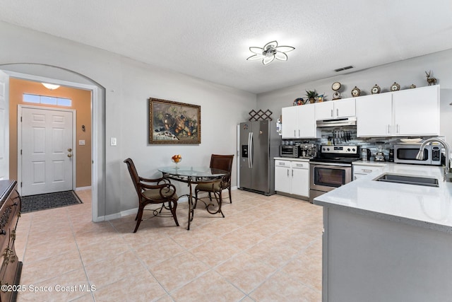 kitchen with white cabinetry, sink, backsplash, light tile patterned floors, and stainless steel appliances