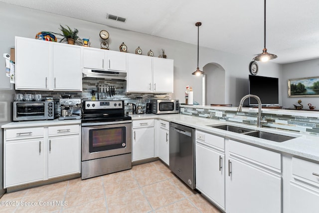 kitchen with pendant lighting, sink, appliances with stainless steel finishes, white cabinetry, and decorative backsplash