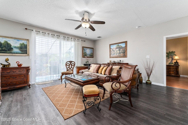 living room featuring ceiling fan, dark hardwood / wood-style floors, and a textured ceiling