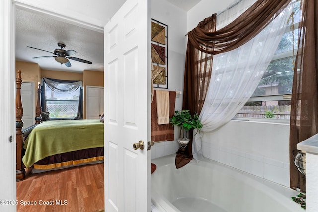 bedroom with ceiling fan, wood-type flooring, and a textured ceiling