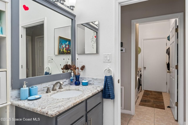 bathroom featuring vanity, tile patterned flooring, and washer and dryer