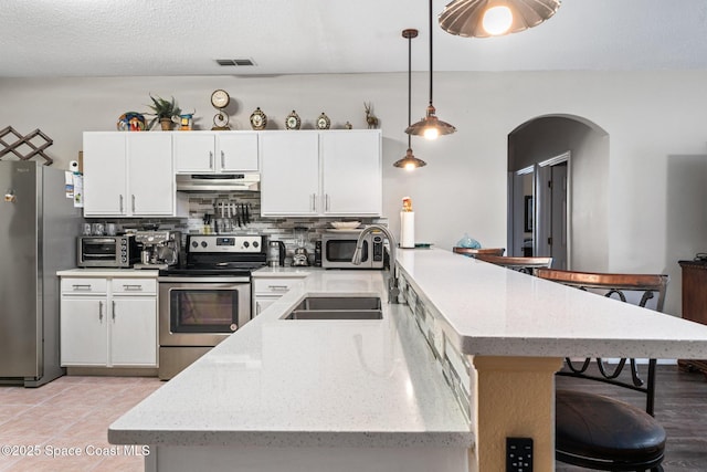 kitchen featuring white cabinetry, decorative light fixtures, and appliances with stainless steel finishes