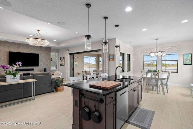 kitchen featuring dishwasher, an island with sink, sink, a chandelier, and a healthy amount of sunlight