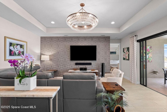 living room with an inviting chandelier, a tray ceiling, and light hardwood / wood-style floors