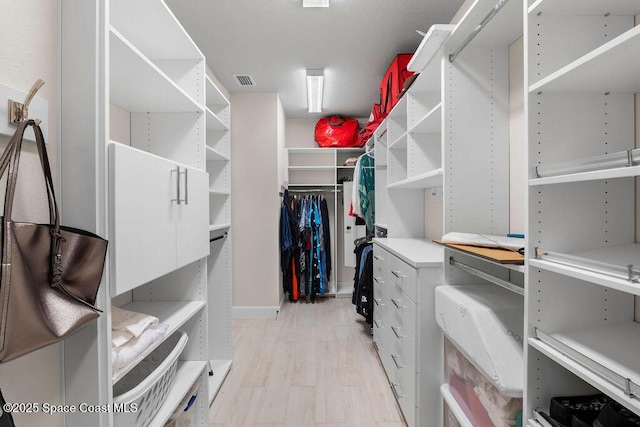 walk in closet with light hardwood / wood-style floors