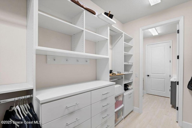 walk in closet with light hardwood / wood-style floors