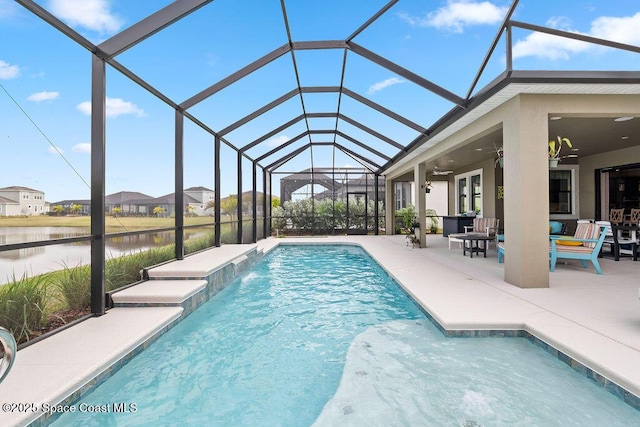 view of swimming pool featuring pool water feature, a patio area, a water view, glass enclosure, and ceiling fan