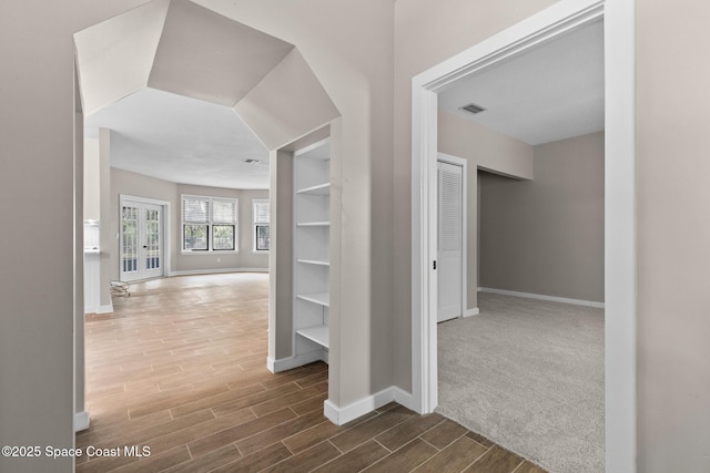 hallway with wood tiled floor, visible vents, and baseboards