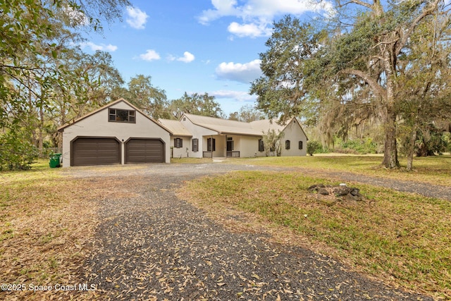 ranch-style house with gravel driveway, an attached garage, and stucco siding