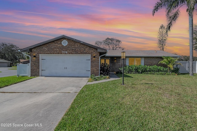 single story home featuring a garage and a lawn