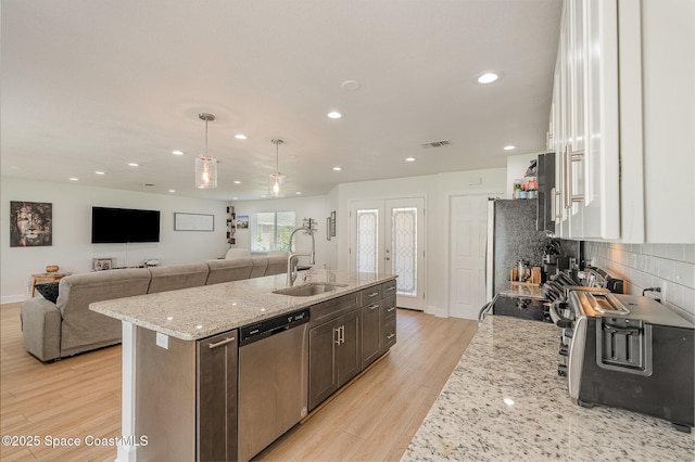 kitchen featuring sink, white cabinets, light stone counters, dark brown cabinetry, and stainless steel appliances