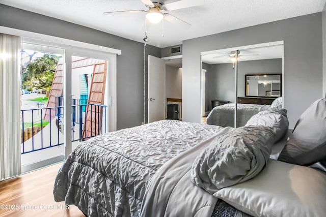 bedroom featuring ceiling fan, hardwood / wood-style floors, access to exterior, a textured ceiling, and a closet