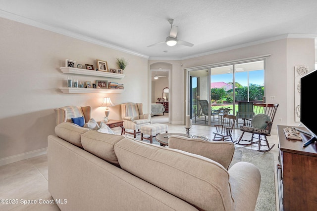 living room with arched walkways, baseboards, a ceiling fan, and crown molding