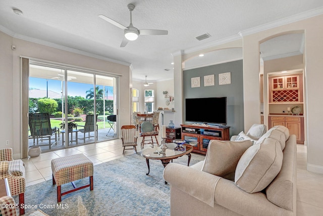 living area with light tile patterned floors, visible vents, ornamental molding, ceiling fan, and a textured ceiling