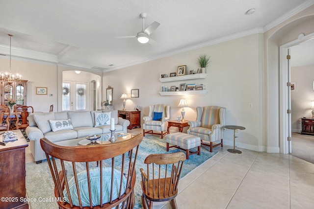 living area featuring arched walkways, light tile patterned flooring, ceiling fan with notable chandelier, baseboards, and ornamental molding