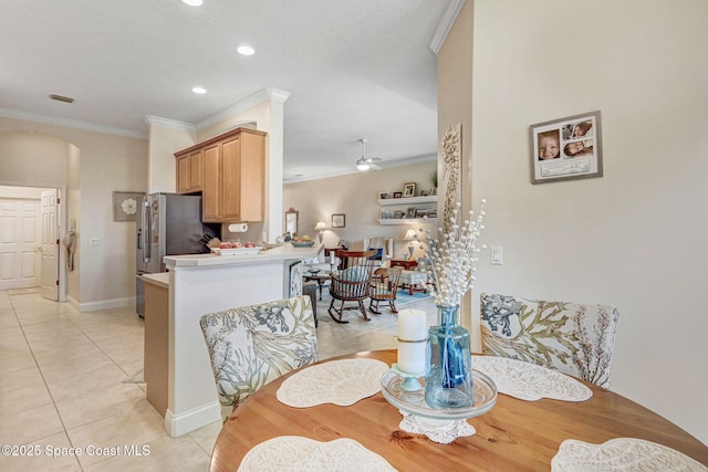 dining room with light tile patterned floors, ceiling fan, arched walkways, and ornamental molding