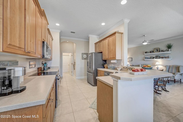 kitchen featuring light tile patterned floors, arched walkways, ornamental molding, a peninsula, and stainless steel appliances