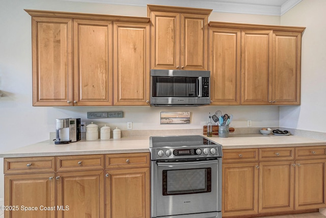 kitchen with ornamental molding, light countertops, appliances with stainless steel finishes, and brown cabinetry