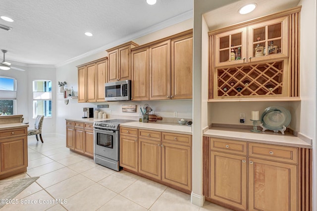 kitchen with light tile patterned floors, light countertops, appliances with stainless steel finishes, and ornamental molding