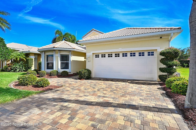 view of front of house featuring a garage, decorative driveway, a tile roof, and stucco siding