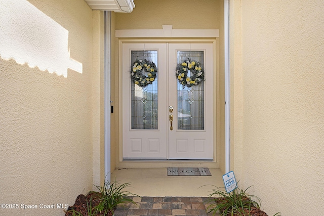 view of exterior entry featuring french doors and stucco siding