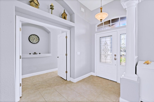 foyer featuring ornate columns, light tile patterned flooring, and a high ceiling