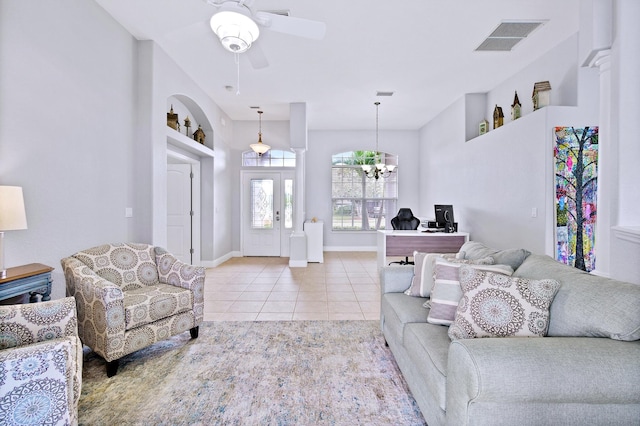 tiled living room with ceiling fan with notable chandelier