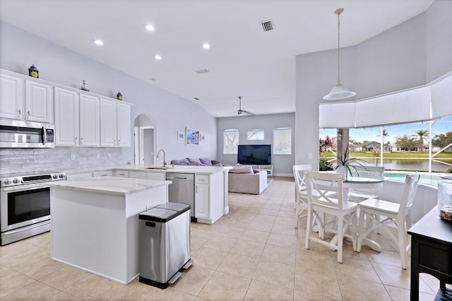 kitchen with appliances with stainless steel finishes, kitchen peninsula, hanging light fixtures, and white cabinets