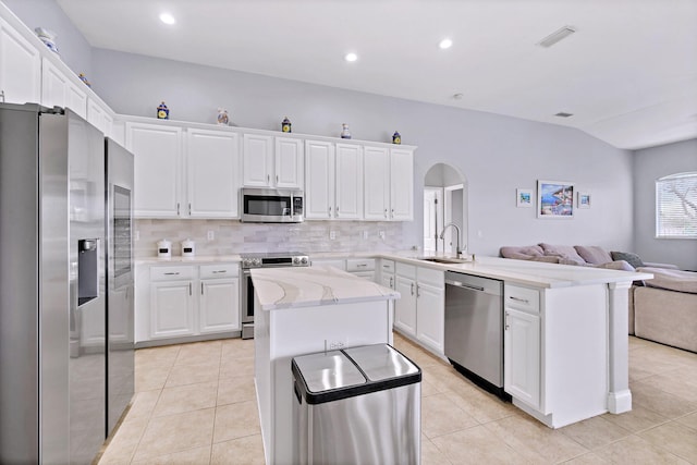 kitchen featuring sink, appliances with stainless steel finishes, white cabinetry, backsplash, and a kitchen island