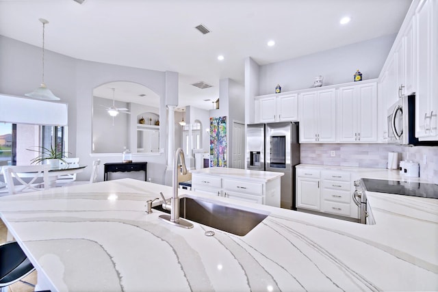 kitchen featuring sink, white cabinetry, a center island, hanging light fixtures, and appliances with stainless steel finishes