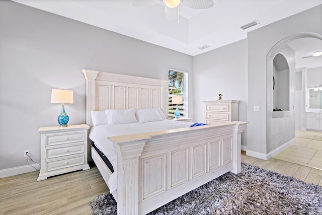 bedroom with ceiling fan, ensuite bath, and light hardwood / wood-style flooring