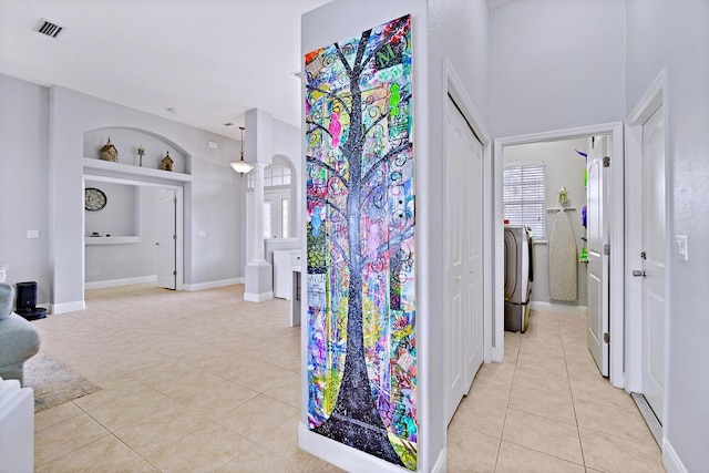 hallway featuring light tile patterned floors, built in shelves, and independent washer and dryer