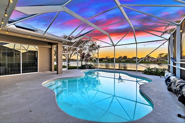 pool at dusk with a water view, glass enclosure, and a patio area